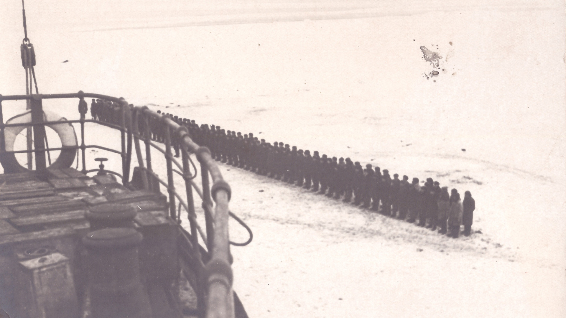 Фотография, сделанная с борта ледокола «Смоленск», пришедшего на спасение «челюскинцев». На льду шеренга людей, более 100 человек. Фото: https://goskatalog.ru