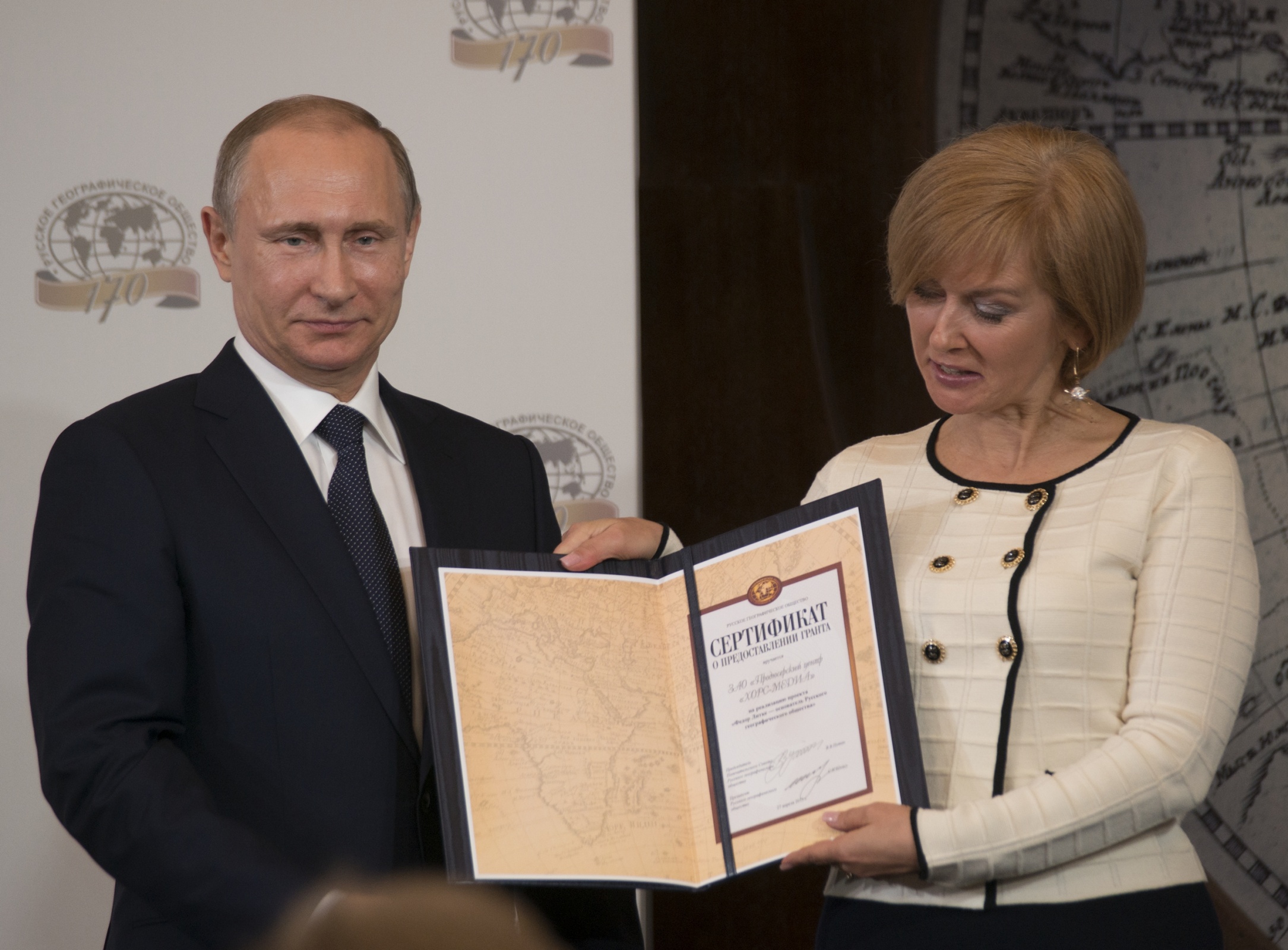 Председатель Попечительского Совета РГО Владимир Путин вручает сертификат о предоставлении гранта руководителю компании 