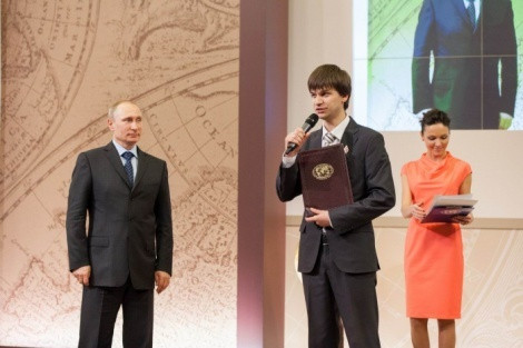 The Chairman of the Board of Trustees of the Russian Geographical Society, the President of Russia Vladimir Putin is handing in the grant of the Russian Geographical Society to the participant of the Summer School Ilya Smirnov